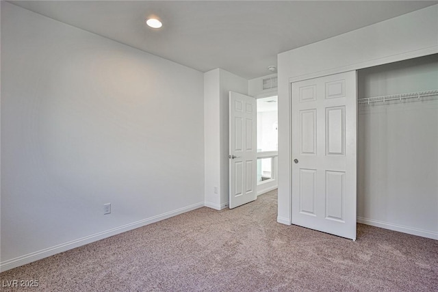 unfurnished bedroom with light carpet, a closet, and baseboards