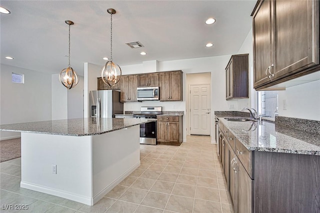 kitchen featuring light tile patterned floors, recessed lighting, appliances with stainless steel finishes, stone countertops, and a sink