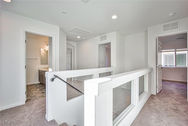 hall with carpet floors, baseboards, visible vents, and attic access