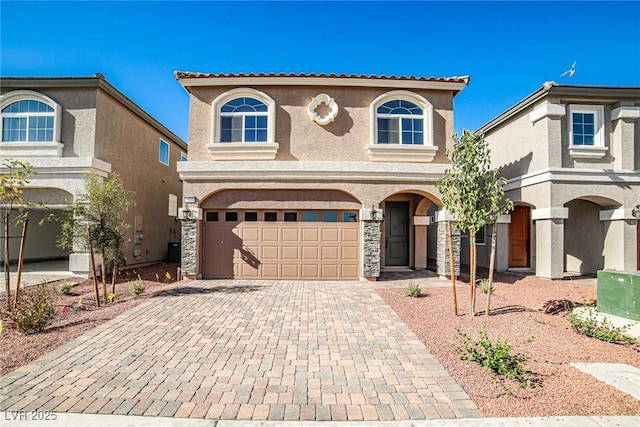 mediterranean / spanish-style house with stone siding, a tiled roof, an attached garage, decorative driveway, and stucco siding