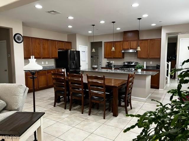 kitchen with visible vents, stove, dark countertops, and freestanding refrigerator