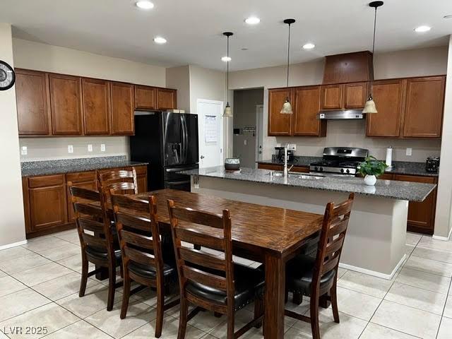 kitchen with brown cabinets, stainless steel gas range, black refrigerator with ice dispenser, under cabinet range hood, and a sink