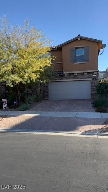 view of front of property featuring driveway, stone siding, and an attached garage