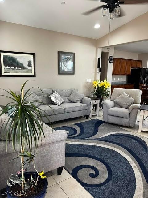 living room featuring lofted ceiling, light tile patterned floors, and ceiling fan