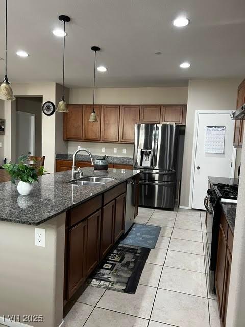 kitchen with recessed lighting, a sink, dark stone countertops, an island with sink, and black appliances