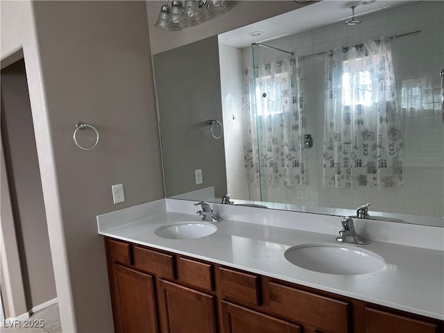 full bathroom with double vanity, tiled shower, and a sink