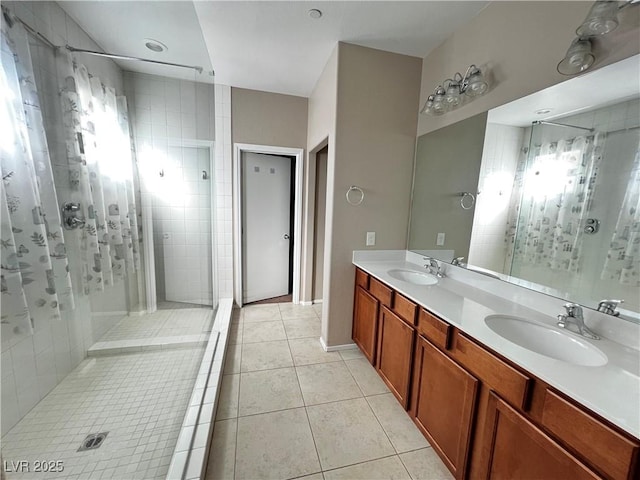 full bathroom featuring double vanity, tiled shower, tile patterned flooring, and a sink