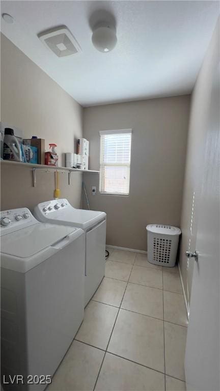 laundry area with laundry area, separate washer and dryer, light tile patterned flooring, and baseboards