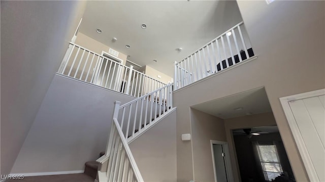 stairway featuring a towering ceiling and baseboards