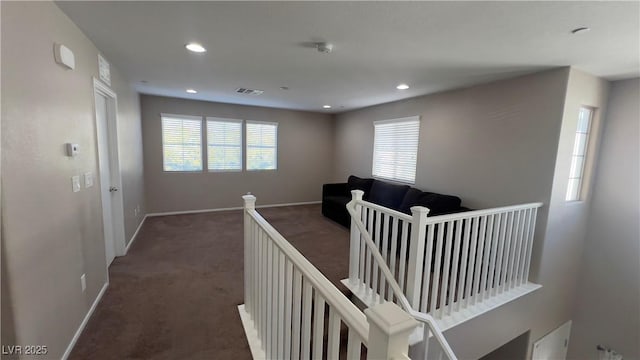 corridor with carpet, visible vents, baseboards, and an upstairs landing