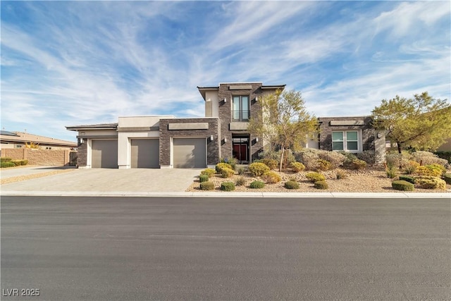 view of front of property with a garage, concrete driveway, stone siding, fence, and stucco siding