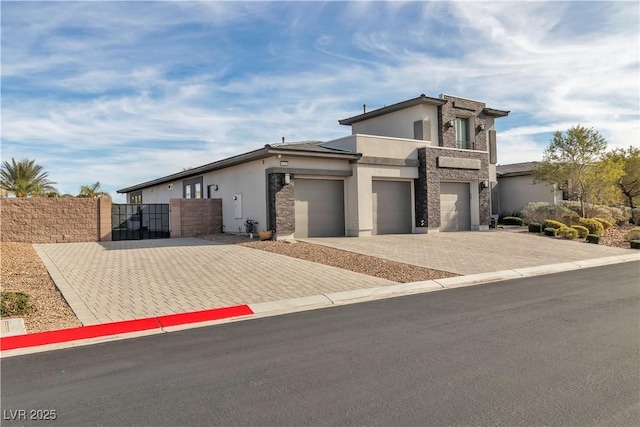 view of front facade featuring stone siding, a gate, decorative driveway, and stucco siding