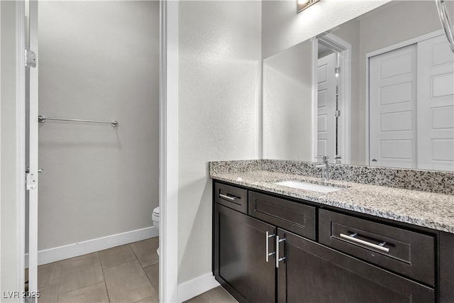 bathroom with toilet, tile patterned floors, baseboards, and vanity