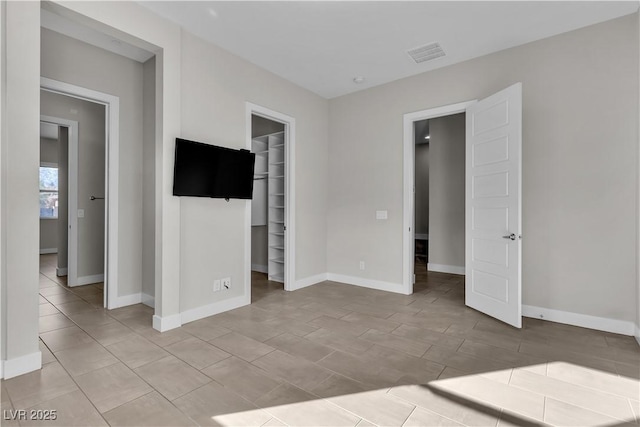 unfurnished bedroom featuring baseboards, a spacious closet, visible vents, and a closet