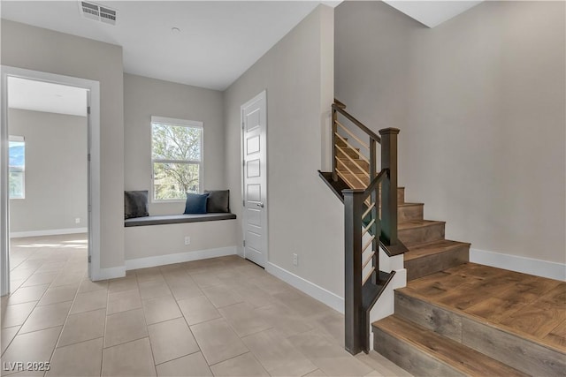 staircase with tile patterned floors, visible vents, and baseboards