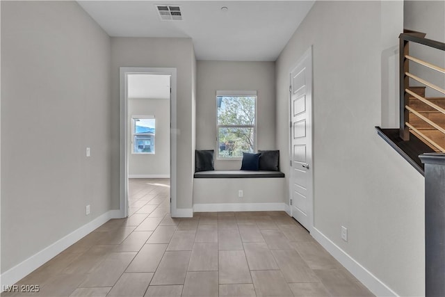 interior space featuring tile patterned floors, visible vents, baseboards, and stairs