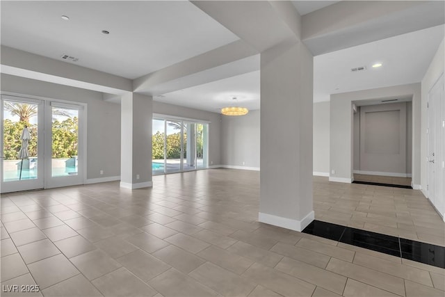 empty room featuring tile patterned flooring, visible vents, a notable chandelier, and baseboards