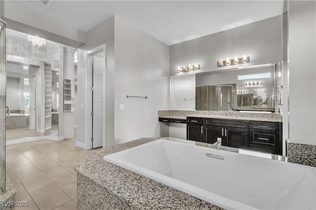 bathroom with a garden tub, tile patterned flooring, and vanity