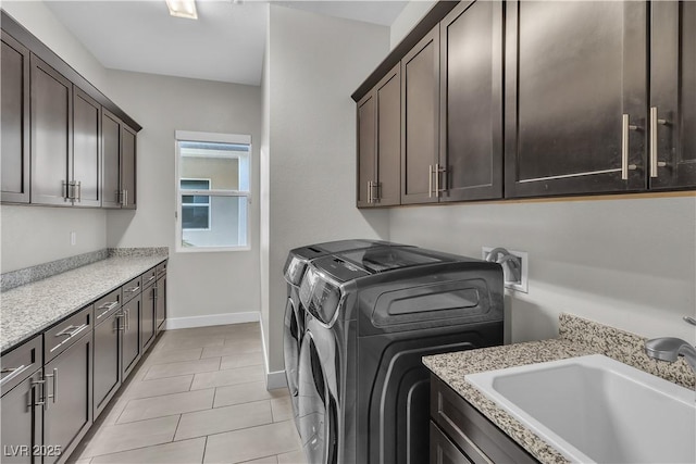 laundry room with light tile patterned floors, a sink, baseboards, washer and dryer, and cabinet space