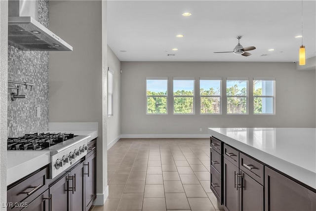 kitchen with light countertops, wall chimney range hood, a healthy amount of sunlight, and stainless steel gas stovetop