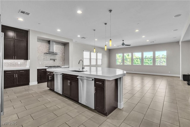 kitchen with tasteful backsplash, light countertops, stainless steel dishwasher, a sink, and wall chimney range hood