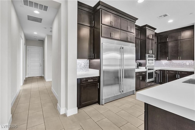 kitchen with appliances with stainless steel finishes, light countertops, visible vents, and backsplash