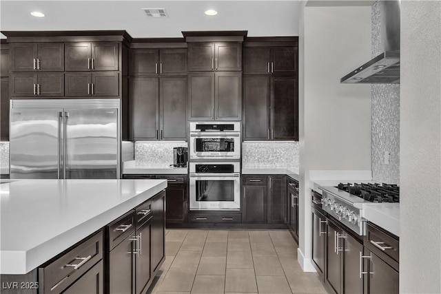 kitchen featuring light countertops, visible vents, decorative backsplash, appliances with stainless steel finishes, and wall chimney range hood