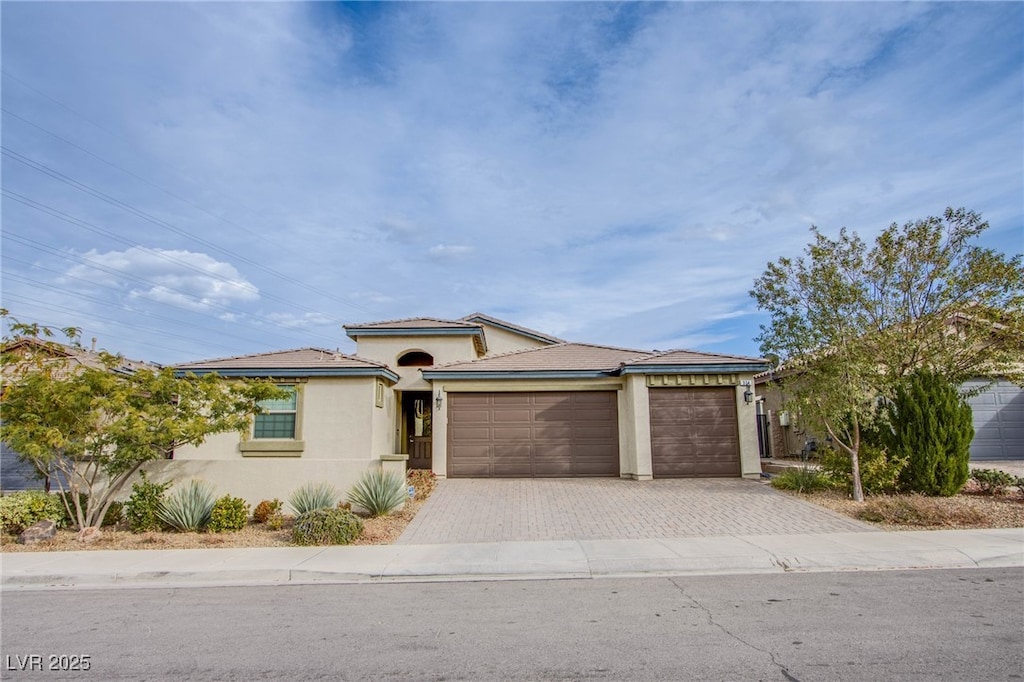 view of front of house featuring a garage, decorative driveway, and stucco siding