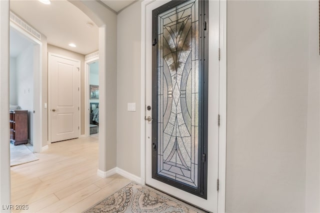 entrance foyer featuring arched walkways, recessed lighting, light wood-type flooring, and baseboards