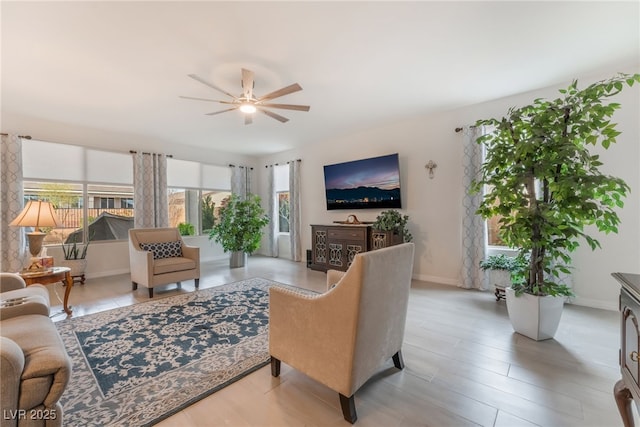 living room with a ceiling fan and baseboards