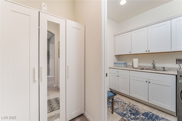 kitchen with washer / dryer, light tile patterned floors, arched walkways, light countertops, and a sink