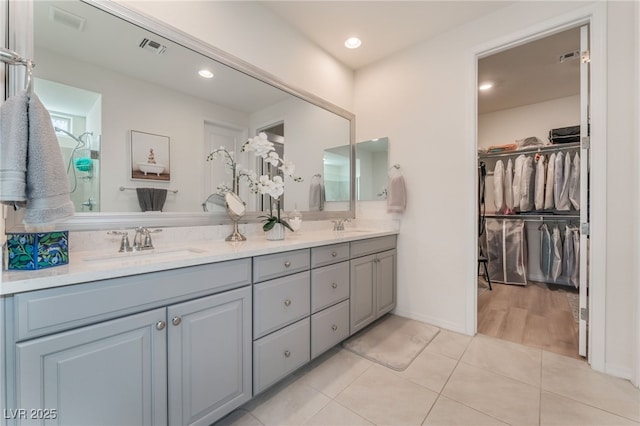 bathroom with tile patterned flooring, a sink, a spacious closet, and double vanity