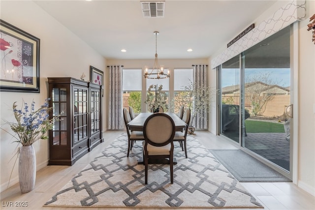 dining room with light wood-style floors, baseboards, visible vents, and a chandelier