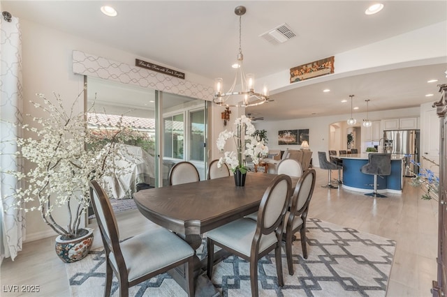 dining room featuring arched walkways, a notable chandelier, recessed lighting, visible vents, and light wood-type flooring