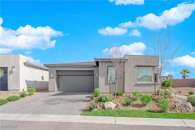 view of front of property with a garage, a tile roof, fence, decorative driveway, and stucco siding