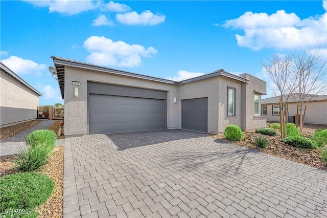 view of front of property featuring a garage, decorative driveway, and stucco siding