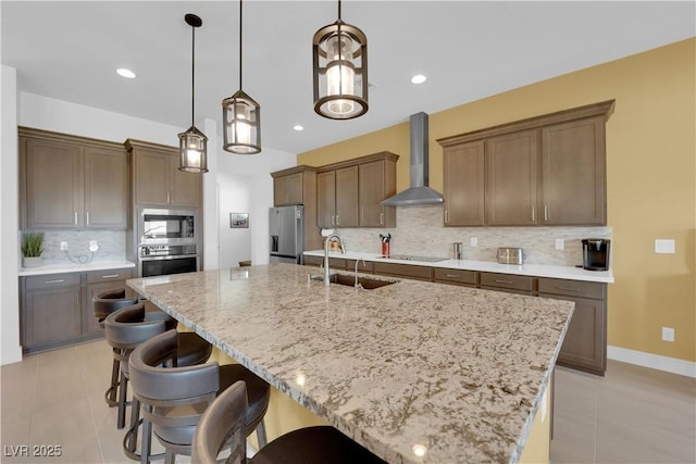 kitchen with wall chimney exhaust hood, a kitchen bar, a sink, and stainless steel appliances