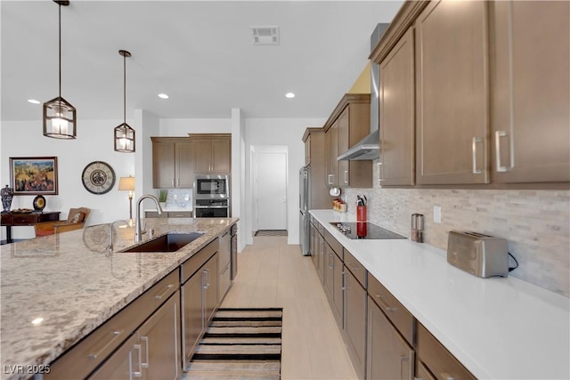 kitchen featuring a sink, visible vents, appliances with stainless steel finishes, decorative backsplash, and decorative light fixtures