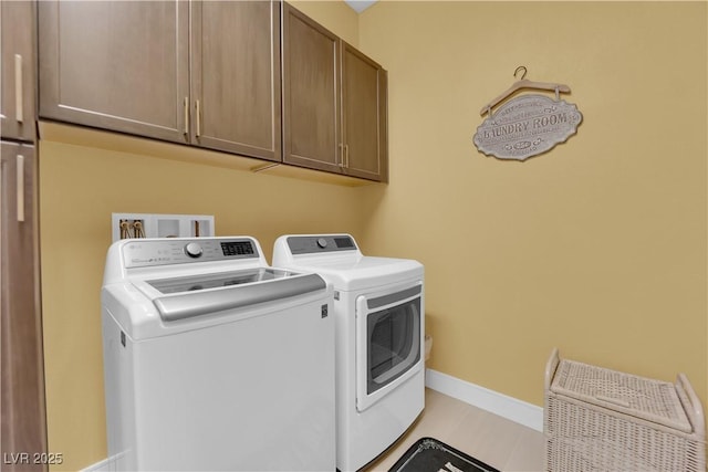 washroom featuring cabinet space, baseboards, and washer and dryer