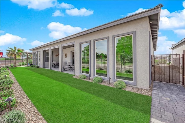 back of property with a patio area, fence, a lawn, and stucco siding