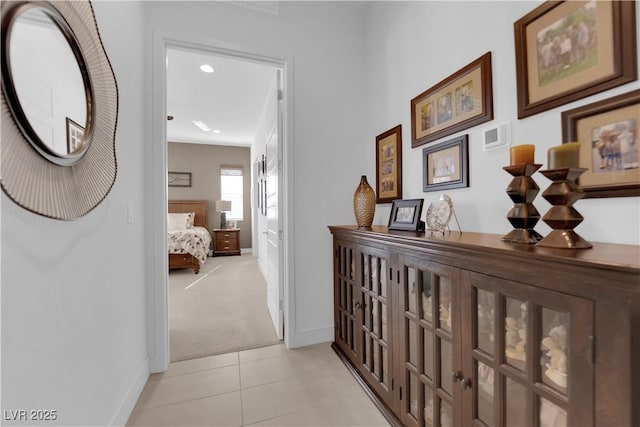 corridor with light tile patterned floors, light carpet, and baseboards