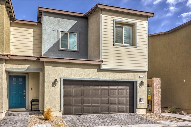 view of property featuring an attached garage, decorative driveway, and stucco siding