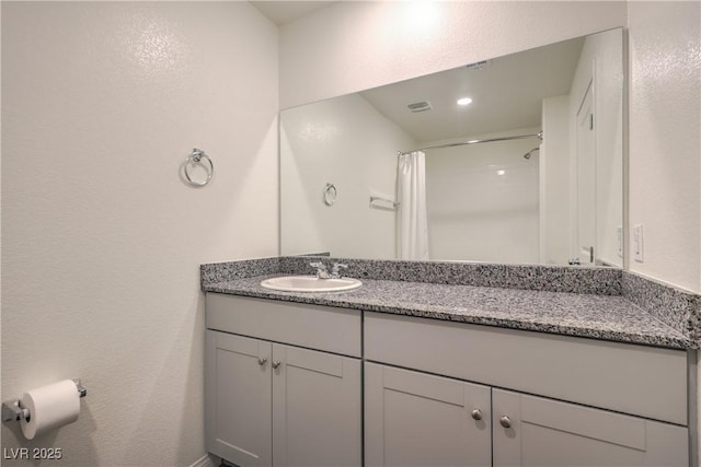 bathroom featuring visible vents, a textured wall, curtained shower, and vanity