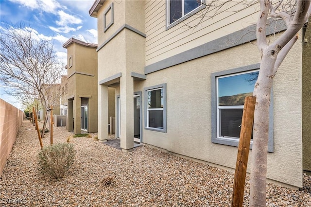 view of side of property with fence and stucco siding