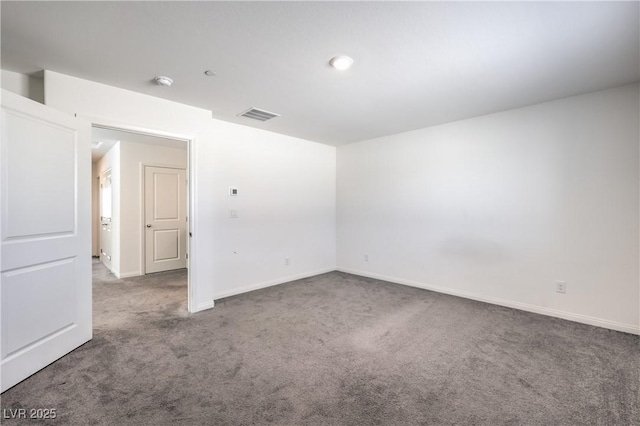 spare room featuring carpet floors, visible vents, and baseboards