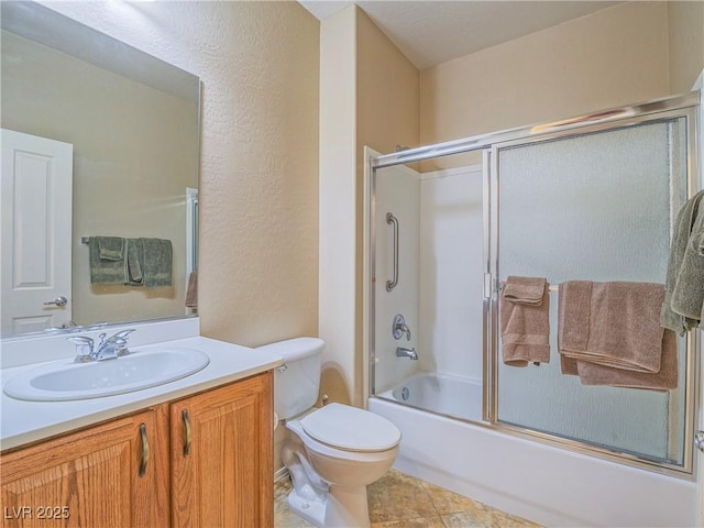 full bathroom featuring a textured wall, tile patterned flooring, toilet, shower / bath combination with glass door, and vanity