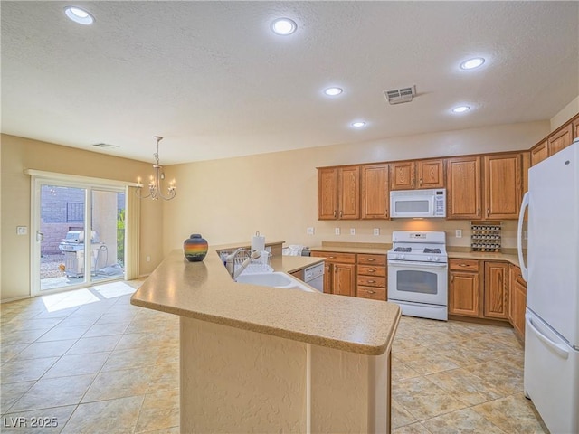 kitchen featuring recessed lighting, visible vents, brown cabinetry, a sink, and white appliances