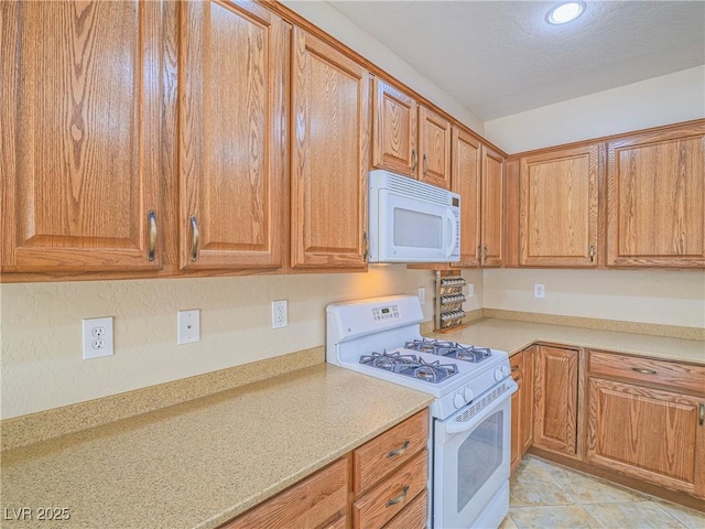 kitchen with brown cabinets, white appliances, and light countertops