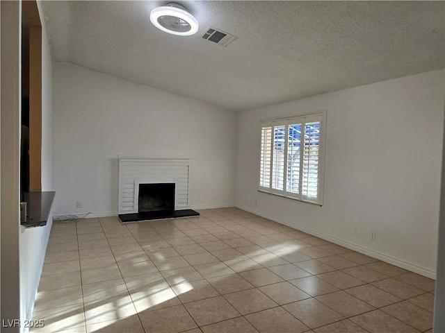 unfurnished living room with lofted ceiling, a textured ceiling, light tile patterned flooring, visible vents, and a brick fireplace