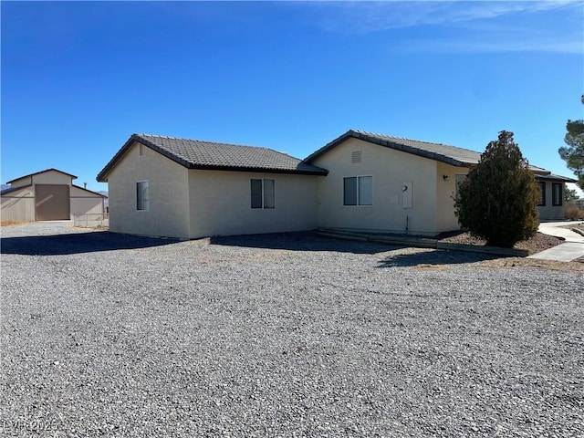 back of property with a tile roof and stucco siding